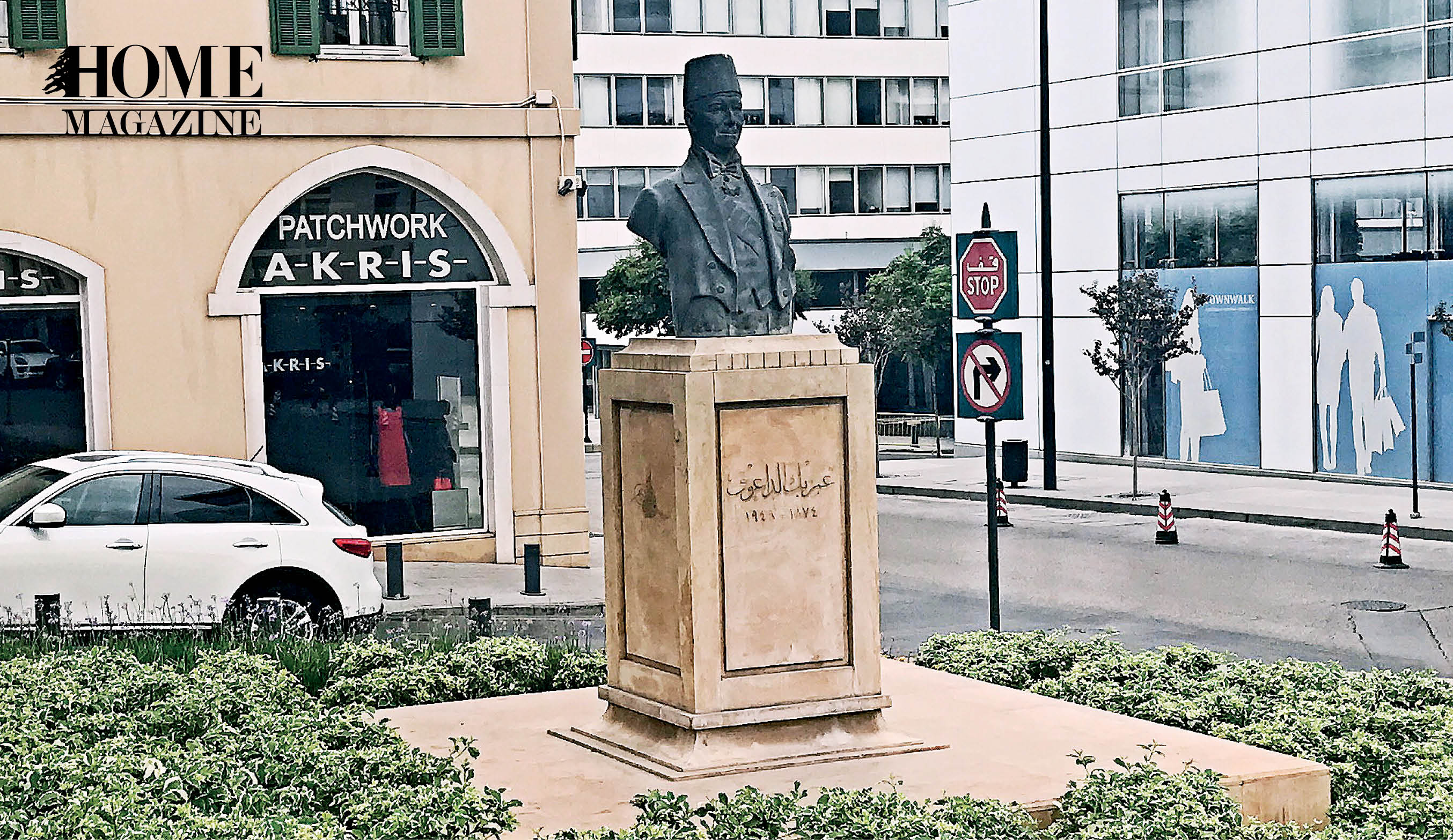 Black statue surrounded by green grass and buildings in background