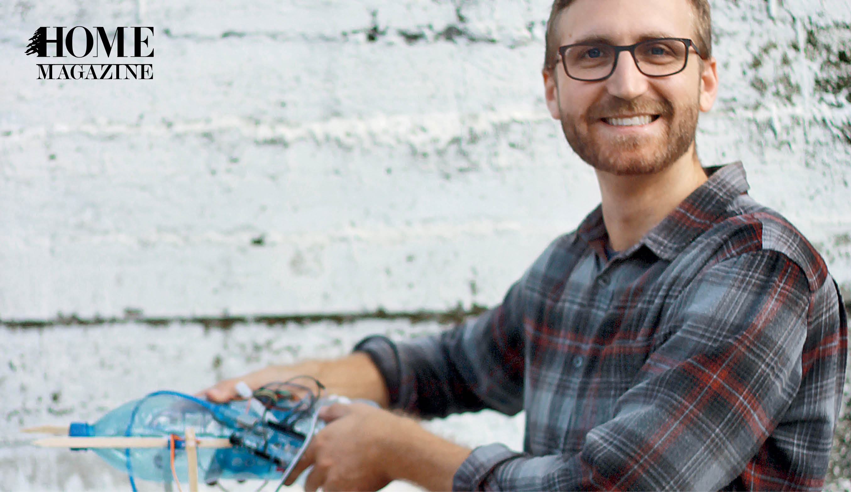 Smiling man wearing eyeglasses and holding object in his hands