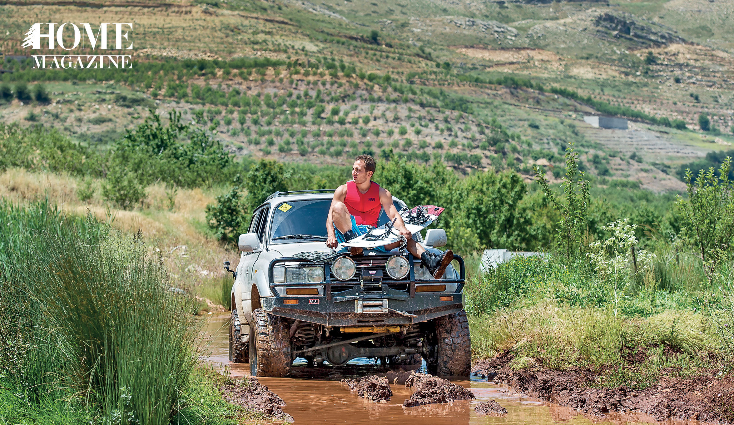 Man holding board and sitting on jeep in green nature