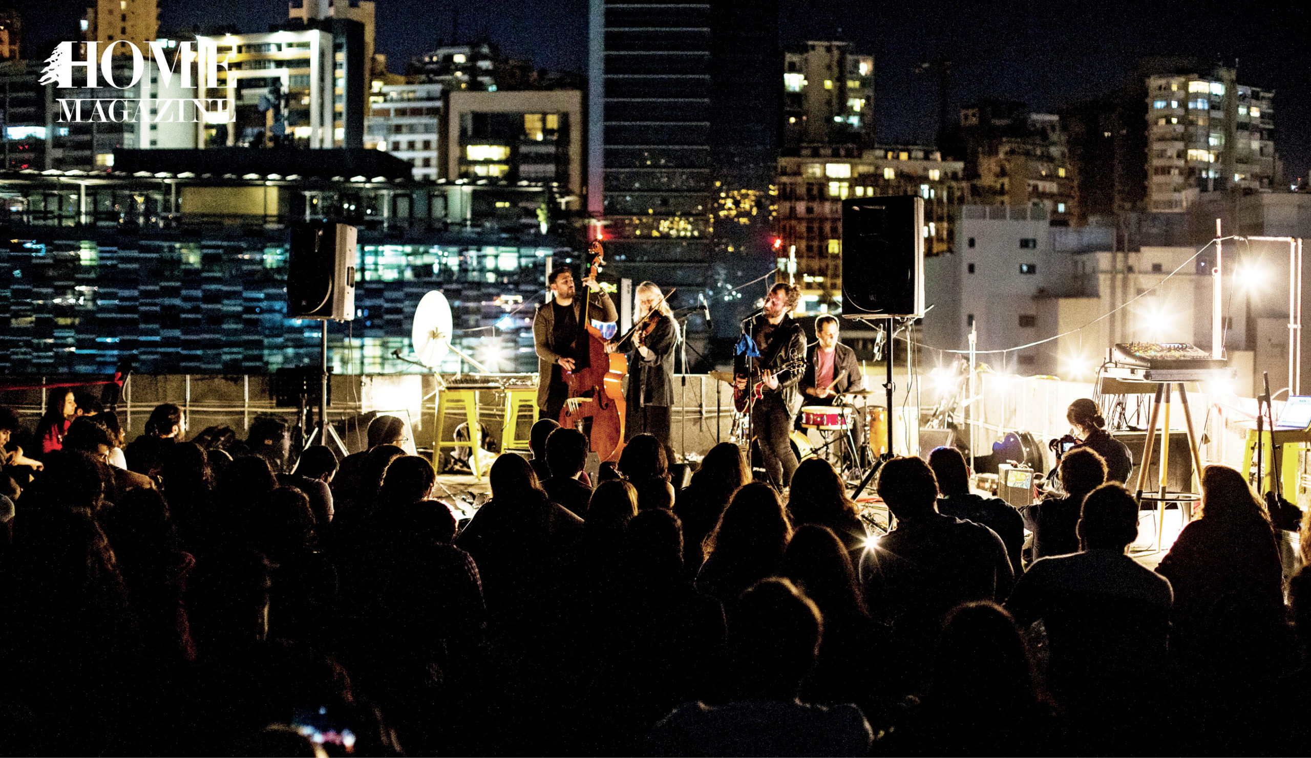 Band performing on a stage with crowd and buildings behind